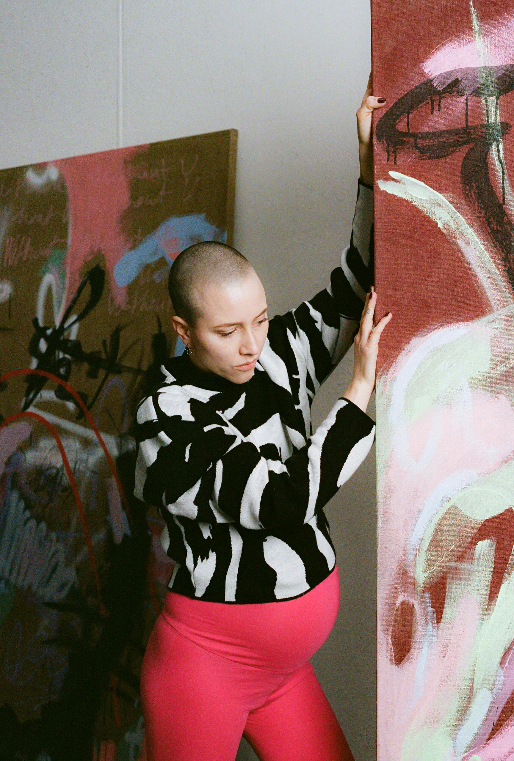 Fruzsina with painting Stylish pregnant woman in MIUMI’s flared maternity trousers moving a large abstract painting.
