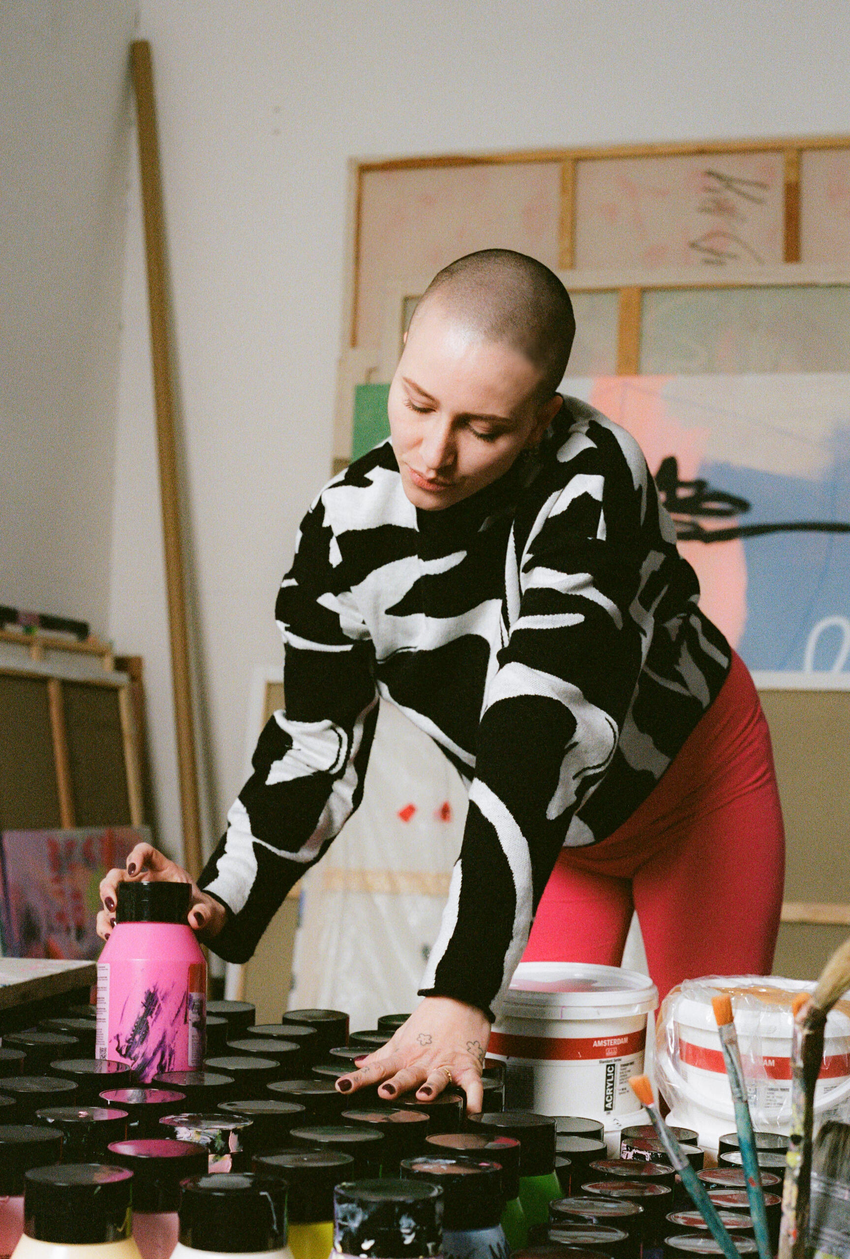 Fruzsina bei Malvorbereitung Schwangere Künstlerin wählt Malutensilien aus und trägt pinke Umstandshose von MIUMI.